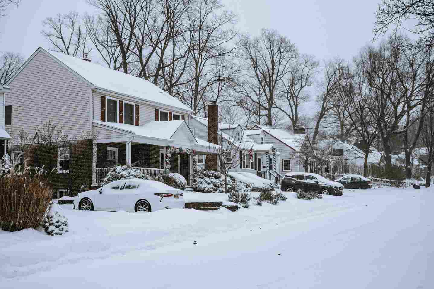 Snow-covered suburban homes without power during daytime blizzard – downed lines and winter blackout scene